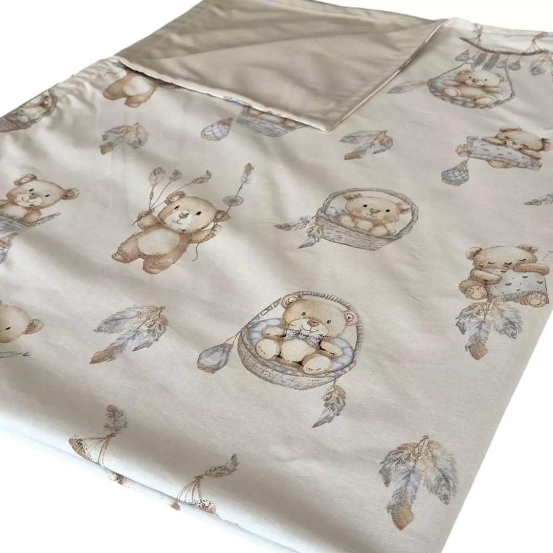 Złożony w pół kocyk do przedszkola z odgiętym rogiem, ukazujący bawełniany wierzch we wzór misie boho i gładki, beżowy spód z minky na białym tle.